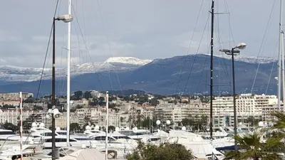 a group of boats docked in a harbor with snow covered mountains at LA PRESQU'ILE T2 PALM BEACH MOURE ROUGE in Cannes