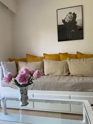 a living room with a couch and a vase with pink flowers at Joli studio calme et central in Cannes