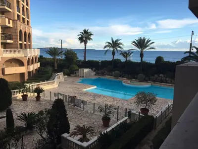 a view of a swimming pool with palm trees and the ocean at Résidence Pierre et Vacance 631 in Cannes