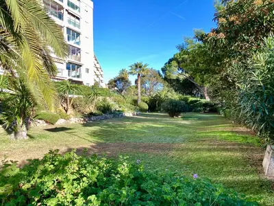 a park with palm trees and a building at Cannes Les Plages By SCLS Locations in Cannes