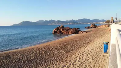 a sandy beach with rocks in the water at Ciel Bleu de Cannes - Appartement Vue Azur avec Piscines et Jardin in Cannes