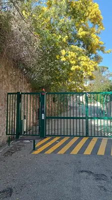 a green gate with yellow stripes in front of a tree at 3 Pièces Vue mer & Iles de Lérins in Cannes