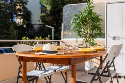 a wooden table with chairs and a hat on a patio at Bright 2bedroom apartment 15min walk to the Palais in Cannes