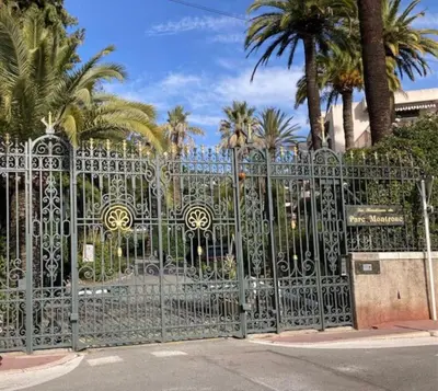 a metal gate with palm trees in the background at Cocon paradisiaque avec piscine, terrasse, jardin au calme absolu in Cannes