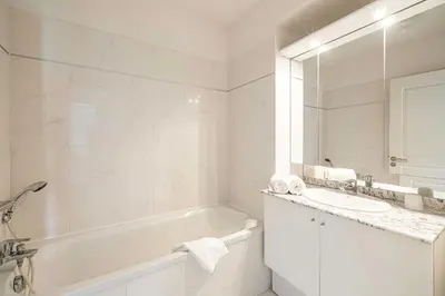 a white bathroom with a tub and a sink at Charming apartment with balcony-pool - Cannes in Cannes