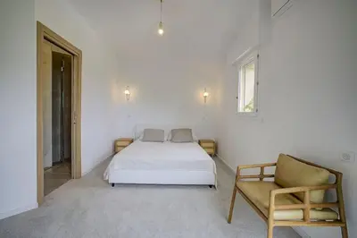 a white bedroom with a bed and a chair at Twin Luxurious Villas 8 BR Pool in Vallauris in Vallauris