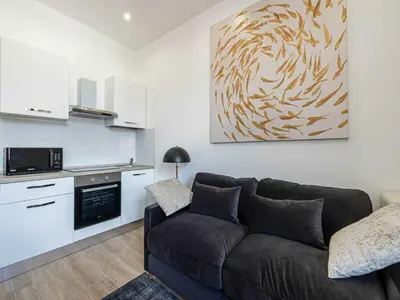 a living room with a couch and a kitchen at Sublime studio - Cannes center - Mobility lease in Cannes