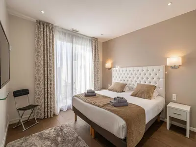 a bedroom with a large bed and a large window at Appt Exclusif - 4BR 8P- Parking - Croisette in Cannes