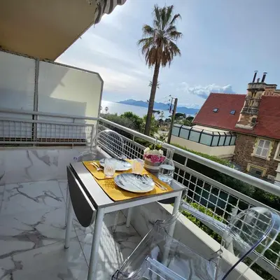 a table on a balcony with a view of the ocean at Victoria - Dr Picaud - 3 Pieces avec climatisation - 5 min des Plages in Cannes