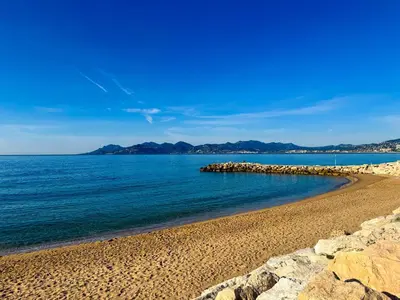 a beach with rocks and the ocean on a clear day at BEAUTIFUL 1 - BR APARTMENT - Next To Rue Antibes in Cannes