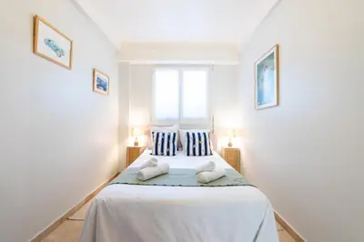 a white bedroom with a large bed with two pillows at Garden level Croisette sea view with garage in Cannes