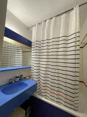 a bathroom with a shower curtain and a blue sink at Appartement Cannes, Piscine - Terrasse, Jardin Privatif - 4 Personnes in Cannes