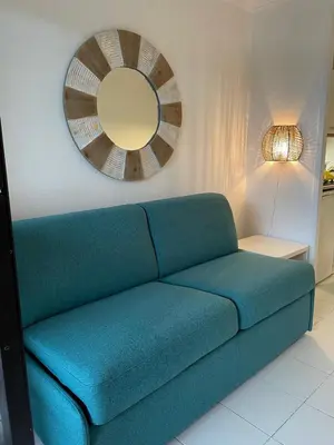 a blue couch in a living room with a mirror at Appartement Cannes, Piscine - Terrasse, Jardin Privatif - 4 Personnes in Cannes