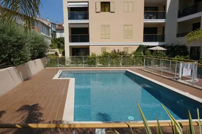 a swimming pool in front of a building at Palm beach apartment with swimming pool in a residence in Cannes
