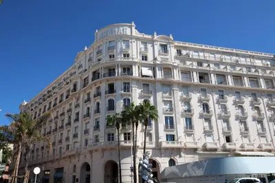 a large white building with palm trees in front of it at 540 Cannes La Croisette - Joli studio au calme coté jardin in Cannes