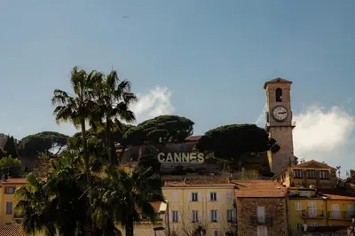 a clock tower on top of a city with a building at Bright and vast studio terrace easy parking Cannes heart of town 1 mn in Cannes