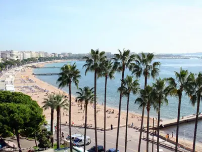 a view of a beach with palm trees and the ocean at Apartment Cannes Parc-2 by Interhome in Cannes