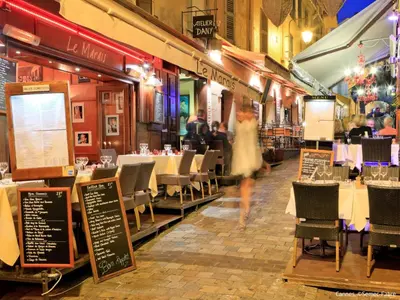 a woman walking through a restaurant with tables and chairs at Apartment Cannes Parc-2 by Interhome in Cannes