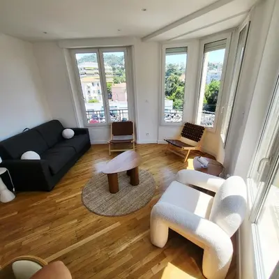 a living room with a couch and tables and windows at Appartement 3 pièces en plein coeur de Cannes in Cannes