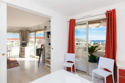 a bedroom with a bed and chairs and a balcony at Résidence 3p De Standing, Vue Mer Et Grande Terrasse - 3P de standing, vue mer et grande terrasse MAE-1613 in Cannes