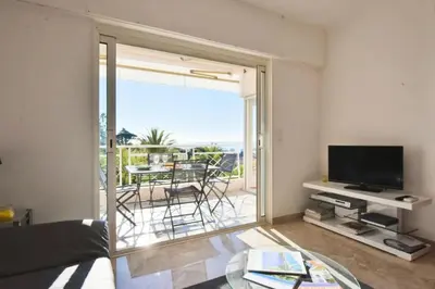 a living room with a television and a table with chairs at Résidence 2p Avec Terrasse, Vue Mer, Piscine Et Parking - 2P avec terrasse, vue mer, piscine et parking MAE-1723 in Cannes