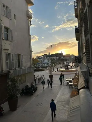 a group of people walking down a street at sunset at CANNES FESTIVALS b in Cannes