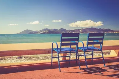 two blue chairs sitting on a ledge near the beach at CANNES plage 2mn/45m2/vue mer/inernet/clim/parking privé in Cannes