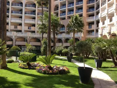 a park in front of a building with palm trees and flowers at Cannes vue mer in Cannes
