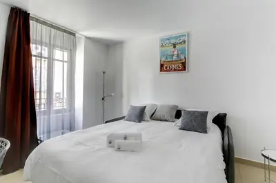 a bedroom with a bed with two cross cushions on it at IMMOGROOM - 8 min from the Palais - AC - Quai St Pierre in Cannes
