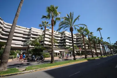 a street in front of a large building with palm trees at Gray d'Albion studio BON500 in Cannes
