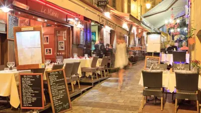 a woman in a white dress walking through a restaurant at Carrousel stud in Cannes