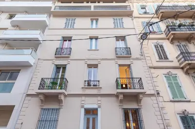 a tall white building with windows and balconies at Charlie Chaplin 2 pièces 3 étoiles calme plein centre de Cannes, 5mn des plages et Palais in Cannes