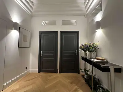 a hallway with two black doors and a vase of flowers at La Guitare 22 - Spacious 1 BR apartment in the center of Cannes, right behind Grand Hotel in Cannes