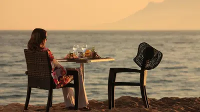 a woman sitting at a table on the beach at Jonquille in Cannes