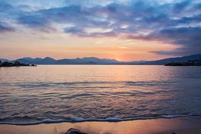 a sunset over a body of water with mountains at Heart of Cannes Amazing design apartment Croisette Top Location Best Seller by OIam Properties in Cannes