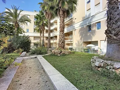 a building with palm trees in front of a yard at Nicolas 8 in Cannes