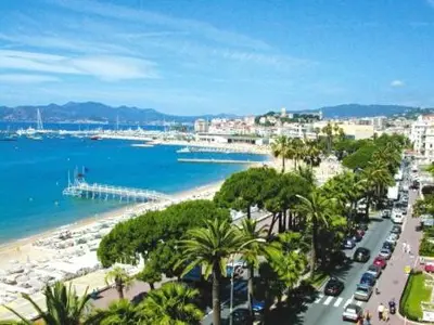 a view of a beach with palm trees and the ocean at Beautiful modern apartment in the heart of Cannes in Cannes