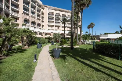 a large building with palm trees and a sidewalk at Résidence Cannes Verrerie - maeva Home - 2 Pièces 5 Personnes Confort MAE-3572 in Cannes