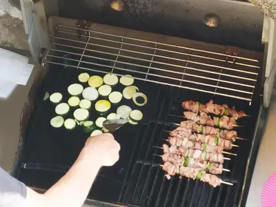 a person is cooking meat and vegetables on a grill at Idéal pied à terre proche Cannes & Sophia, parking in Mougins