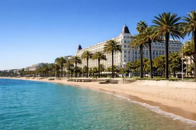 a bedroom with a bed and a table and a kitchen at Studio design - 5 min à pied du Palais & plages in Cannes