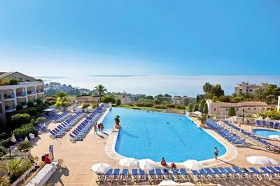 a large swimming pool with blue and white chairs and the ocean at Résidence Cannes Villa Francia - maeva Home - Appartement 3 Pièces 6 Personnes - Confort MAE-7944 in Cannes