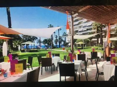 a restaurant with white tables and chairs and a building at Ibis croisette in Cannes