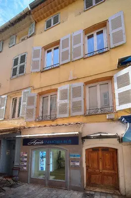 a building with white shuttered windows and a store at Charmant 2 pièces MEYNADIER-FORVILLE A1B209 in Cannes