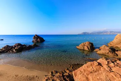 a beach with rocks and the ocean with a cruise ship at à 10 min de la Croisette - pieds dans la mer in Cannes