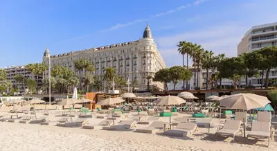 a beach with chairs and umbrellas and a building at Arundel Croisette 100m Beach, Palais Free Parking AC Fibre in Cannes