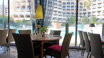 a dining room with a table and chairs and a large window at Appartement 607, vue mer, 4 personnes By Palmazur Vacances in Cannes