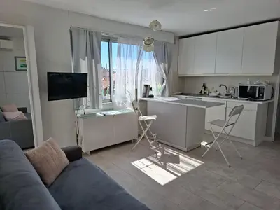 a living room with a couch and a kitchen with a window at Macé9 in Cannes