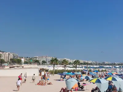a group of people on a beach with umbrellas at Palais Miramar - Cannes Croisette - Across the Beach - Next to Carlton Hotel in Cannes
