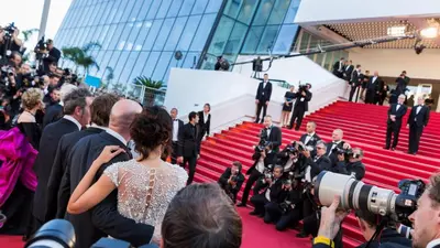 a group of people on a red carpet with a camera at Palais Azur in Cannes