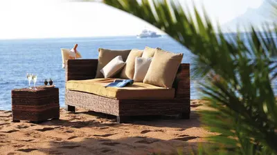 a rattan couch sitting on the beach with the ocean at Pegase in Cannes